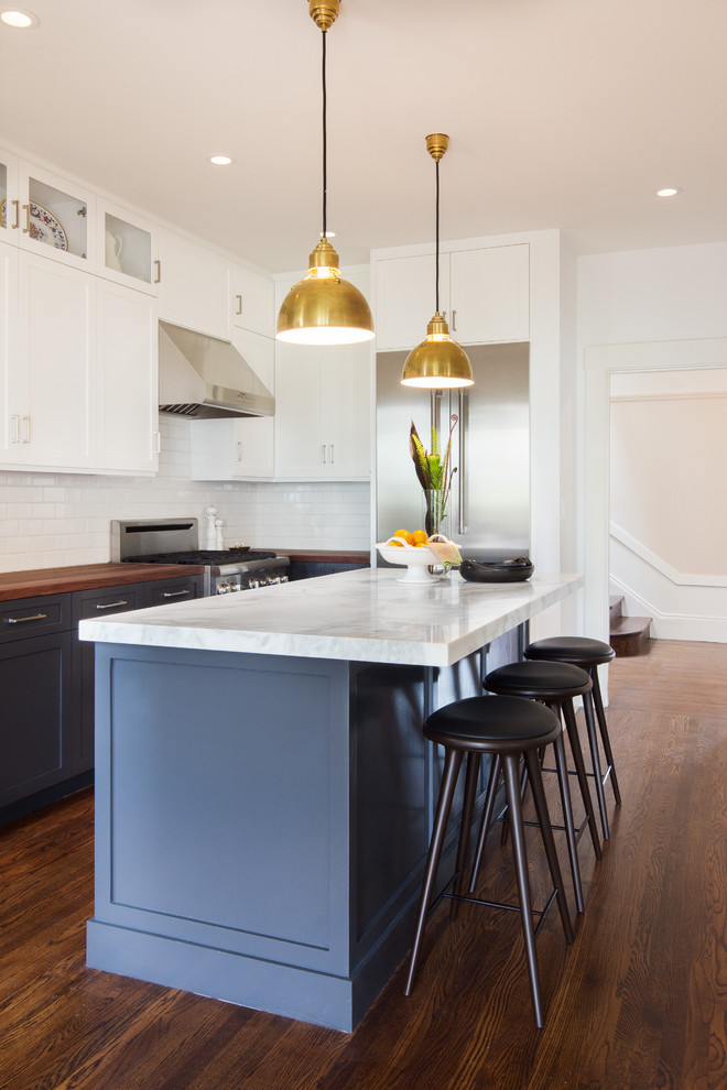 Design ideas for a mid-sized contemporary l-shaped eat-in kitchen in San Francisco with a farmhouse sink, recessed-panel cabinets, white cabinets, wood benchtops, white splashback, ceramic splashback, stainless steel appliances, medium hardwood floors and with island.