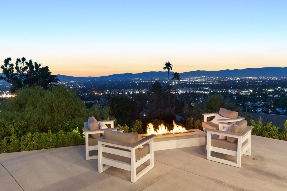 Large trendy two-story and backyard stucco and concrete white patio photo in Los Angeles with a fire pit and no cover