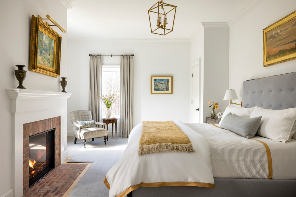 Cottage medium tone wood floor and brown floor bedroom photo in New York with white walls, a standard fireplace and a brick fireplace