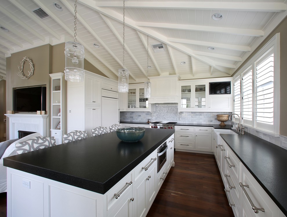 Inspiration for a mid-sized traditional u-shaped open plan kitchen in Tampa with a farmhouse sink, beaded inset cabinets, white cabinets, granite benchtops, grey splashback, stone tile splashback, panelled appliances, dark hardwood floors and with island.