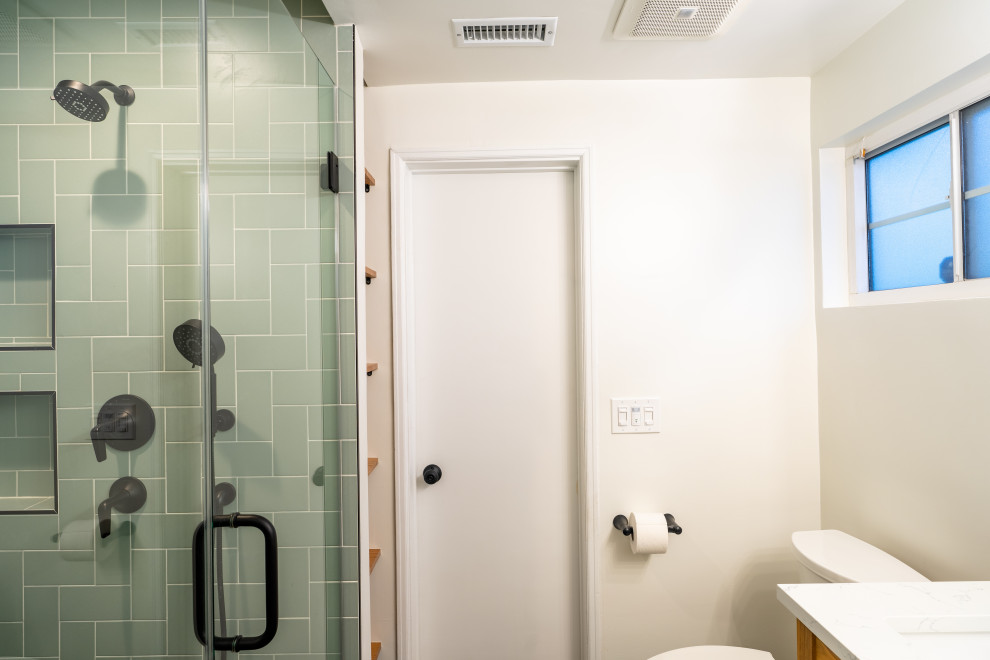 Идея дизайна: маленькая главная ванная комната в стиле модернизм с фасадами в стиле шейкер, светлыми деревянными фасадами, душем в нише, унитазом-моноблоком, зеленой плиткой, керамической плиткой, белыми стенами, бетонным полом, накладной раковиной, мраморной столешницей, черным полом, душем с распашными дверями, белой столешницей, тумбой под две раковины и напольной тумбой для на участке и в саду