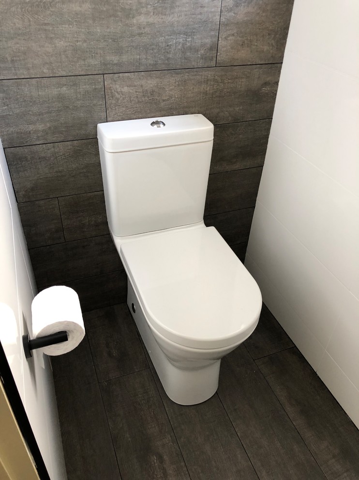 Inspiration for a small modern powder room in Sydney with a two-piece toilet, ceramic tile, ceramic floors, flat-panel cabinets, white cabinets, white tile, white walls, an integrated sink, engineered quartz benchtops and brown floor.