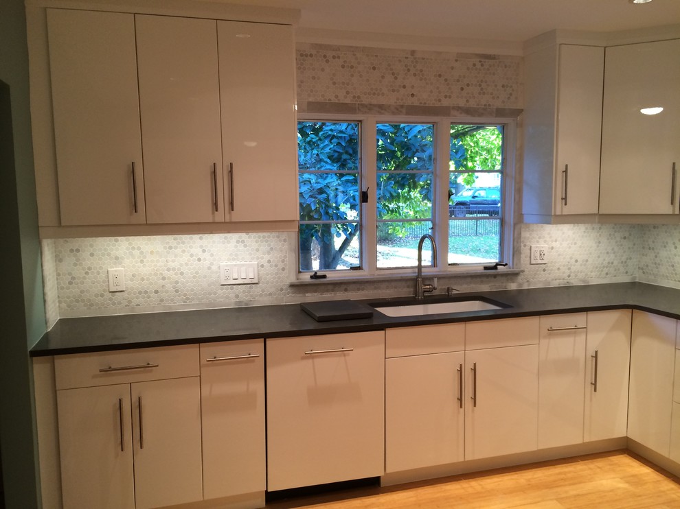 Inspiration for a mid-sized contemporary kitchen in Newark with an undermount sink, white cabinets, quartz benchtops, white splashback, mosaic tile splashback, white appliances, bamboo floors and flat-panel cabinets.