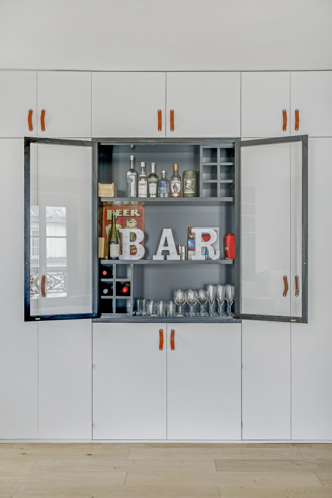 This is an example of an industrial single-wall wet bar in Paris with no sink, glass-front cabinets, black cabinets, wood benchtops, black splashback, timber splashback, light hardwood floors, brown floor and black benchtop.