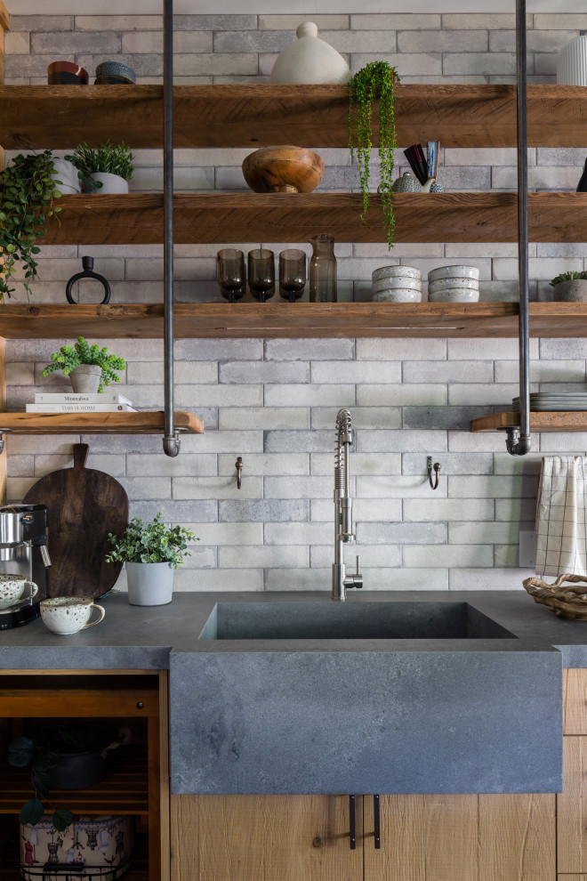 Photo of a medium sized industrial single-wall kitchen/diner in Vancouver with a built-in sink, shaker cabinets, light wood cabinets, grey splashback, brick splashback, stainless steel appliances, medium hardwood flooring, an island, brown floors, grey worktops and concrete worktops.