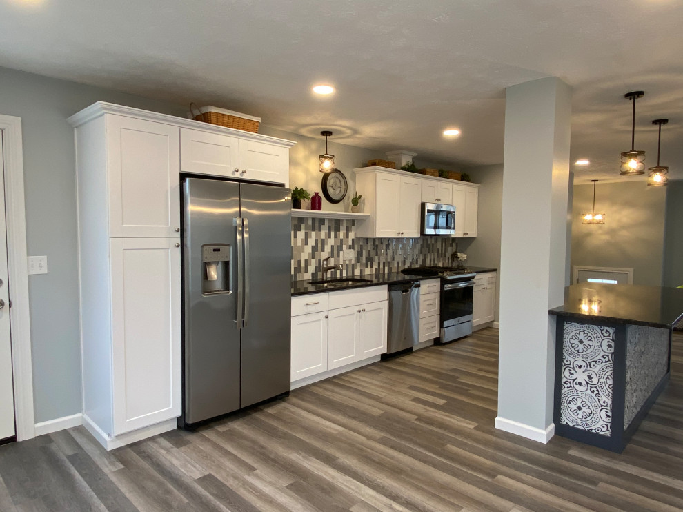 Large transitional l-shaped vinyl floor and gray floor open concept kitchen photo in Cincinnati with an undermount sink, raised-panel cabinets, white cabinets, granite countertops, multicolored backsplash, ceramic backsplash, stainless steel appliances, an island and black countertops