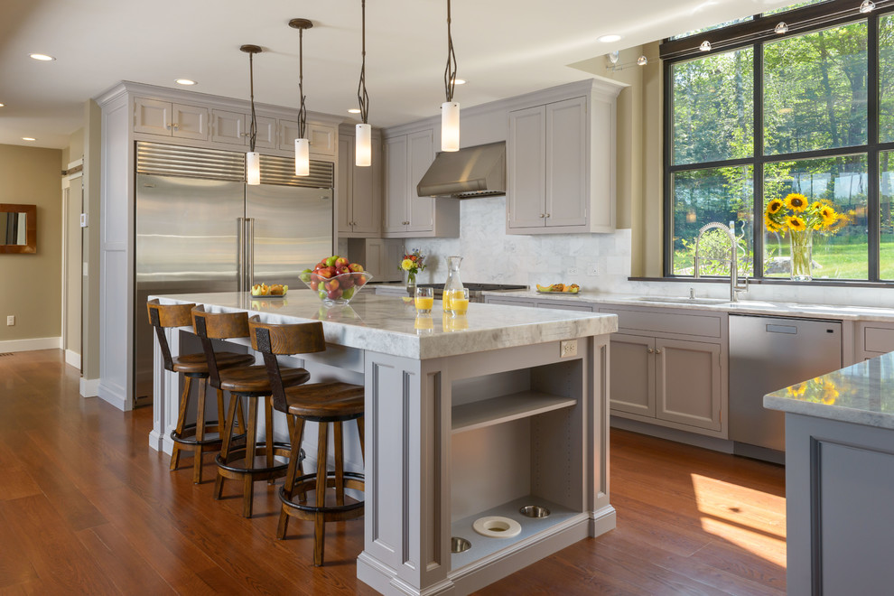Design ideas for a large transitional l-shaped open plan kitchen in Boston with an undermount sink, recessed-panel cabinets, stainless steel appliances, with island, white cabinets, marble benchtops, grey splashback, marble splashback, medium hardwood floors and brown floor.