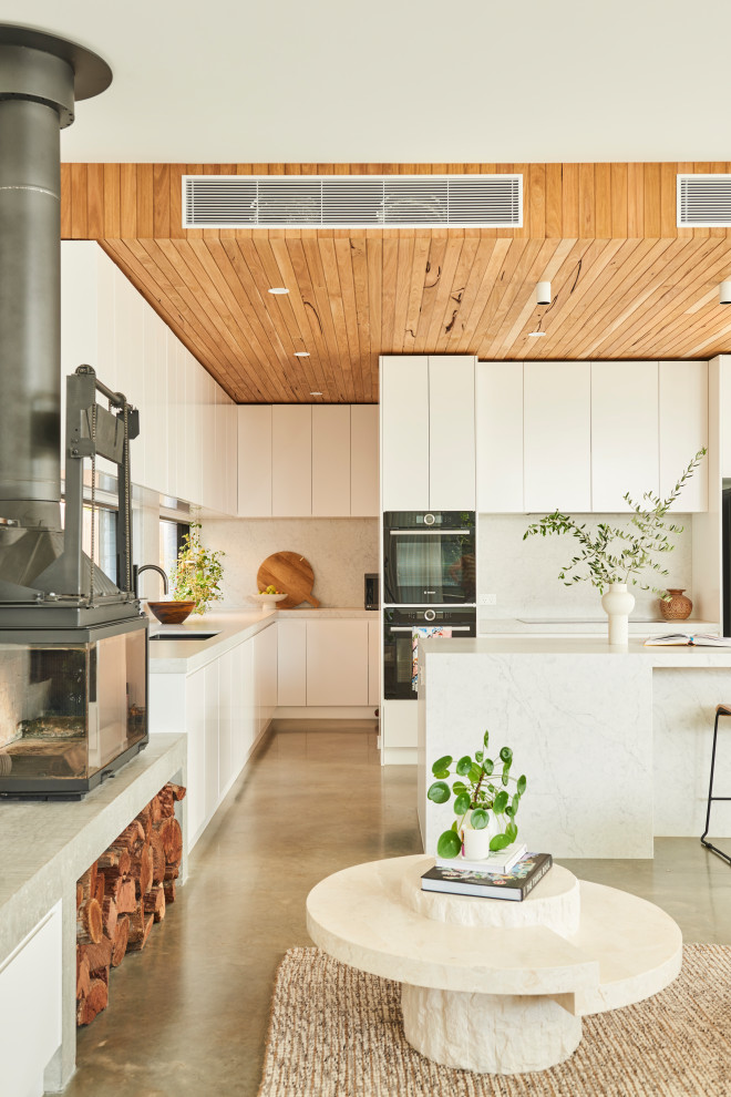 Exempel på ett stort modernt vit vitt kök, med en undermonterad diskho, släta luckor, vita skåp, bänkskiva i kvarts, vitt stänkskydd, betonggolv, en köksö och grått golv