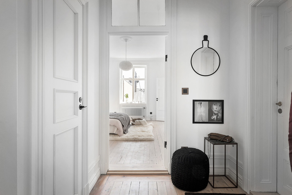 Design ideas for a mid-sized traditional hallway in Stockholm with white walls and light hardwood floors.