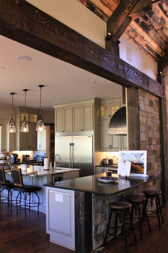 Huge mountain style l-shaped open concept kitchen photo with an undermount sink, quartz countertops, beige backsplash, stone tile backsplash, stainless steel appliances and an island