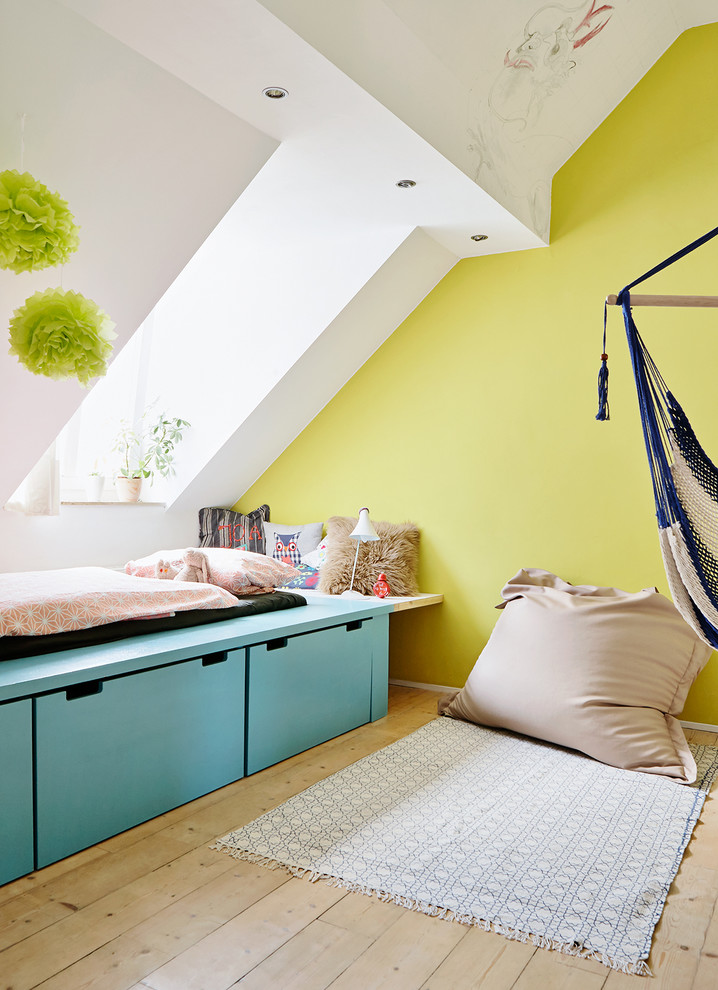 This is an example of a mid-sized scandinavian gender-neutral kids' bedroom for kids 4-10 years old in Hamburg with light hardwood floors and green walls.