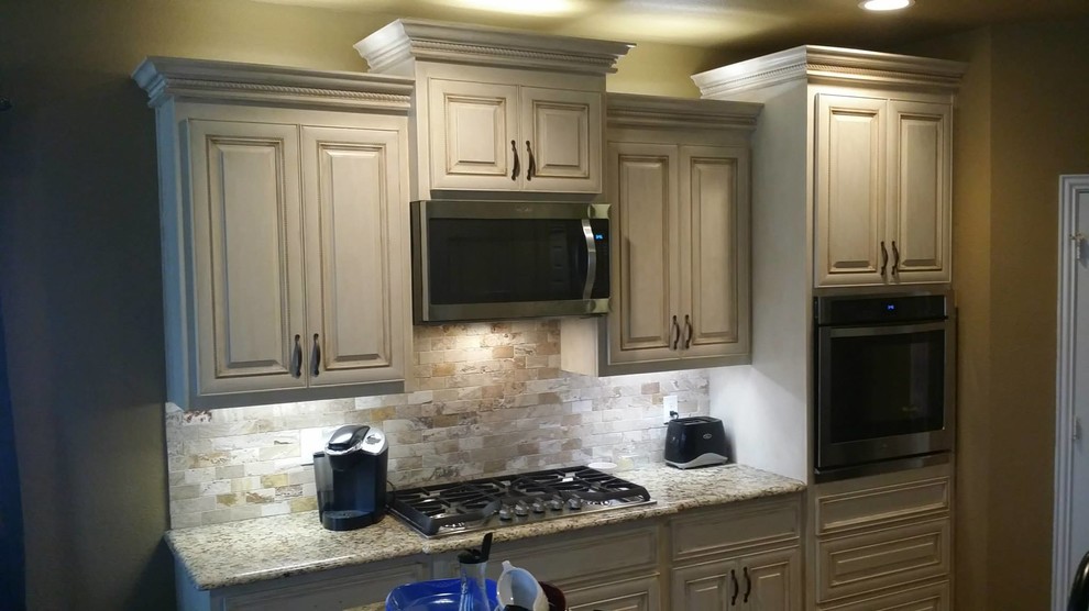 This is an example of a mid-sized transitional eat-in kitchen in Dallas with an undermount sink, raised-panel cabinets, grey cabinets, granite benchtops, beige splashback, cement tile splashback, white appliances, travertine floors and with island.