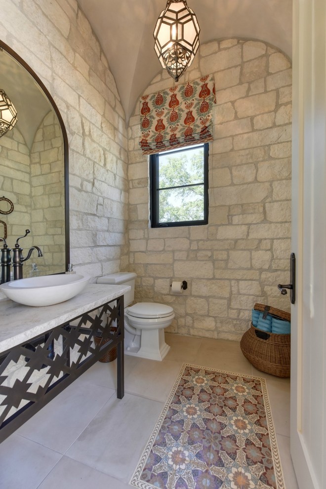 Inspiration for an expansive mediterranean powder room in Sacramento with furniture-like cabinets, a two-piece toilet, beige tile, stone slab, white walls, travertine floors, a vessel sink, limestone benchtops, beige floor and white benchtops.