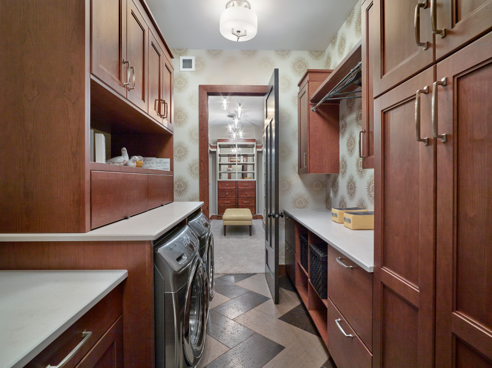 This is an example of a mid-sized arts and crafts galley laundry room in Edmonton with recessed-panel cabinets, brown cabinets, quartz benchtops, travertine floors, a side-by-side washer and dryer, multi-coloured floor, white benchtop and wallpaper.