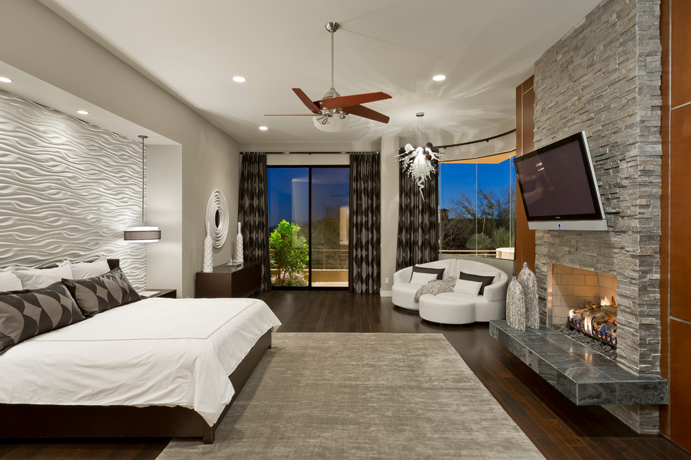 This is an example of an expansive contemporary master bedroom in Phoenix with grey walls, a standard fireplace and a stone fireplace surround.