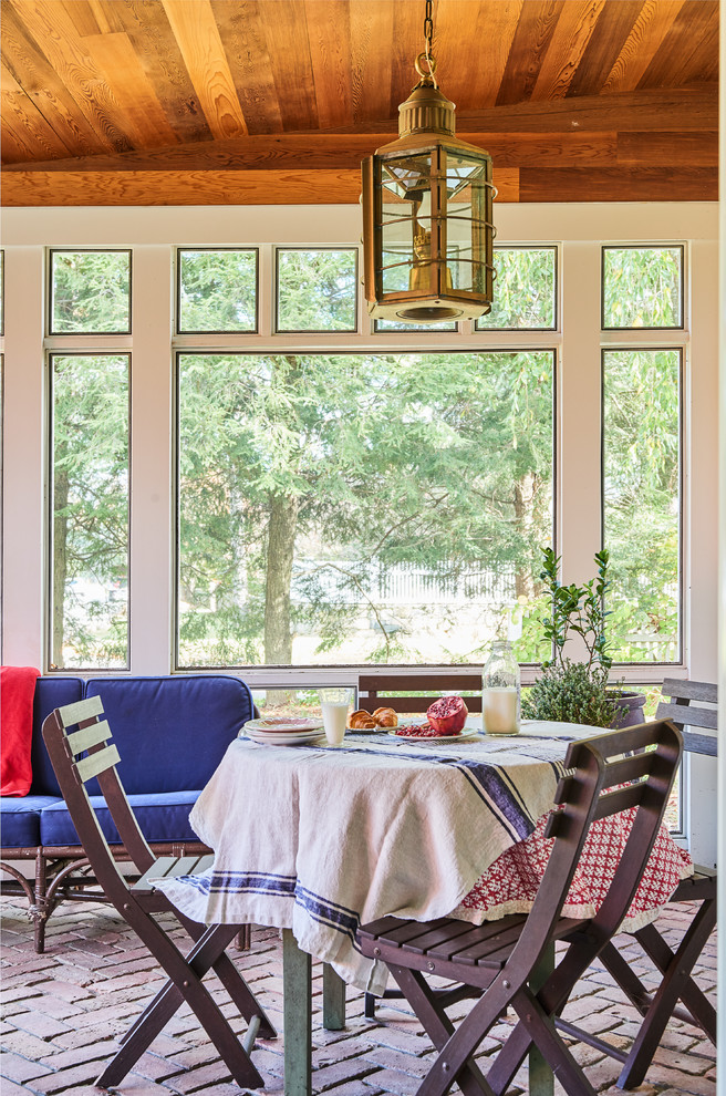 Large cottage brick screened-in front porch idea in New York with a roof extension