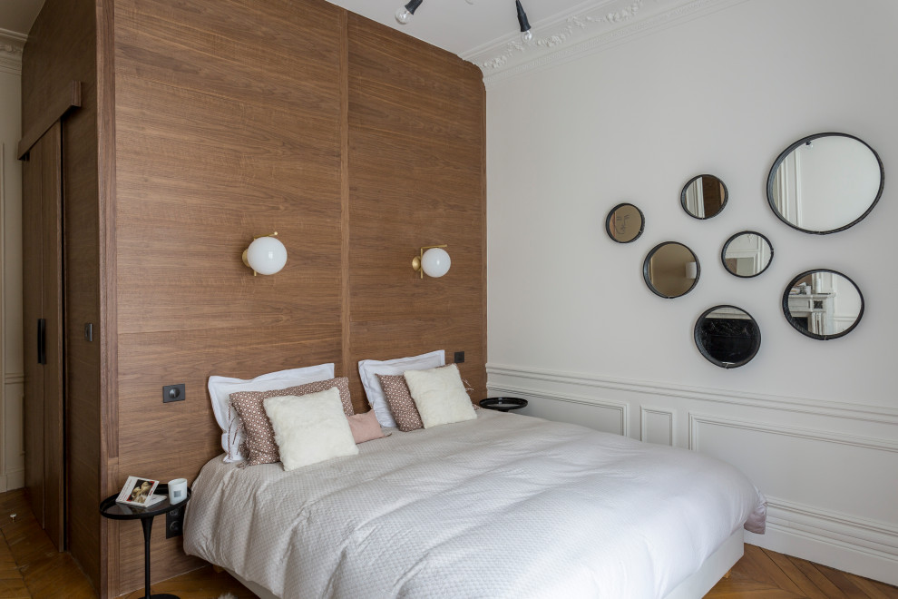 Cette photo montre une grande chambre parentale tendance en bois avec un mur blanc, un sol en bois brun, une cheminée standard, un manteau de cheminée en pierre et un sol marron.
