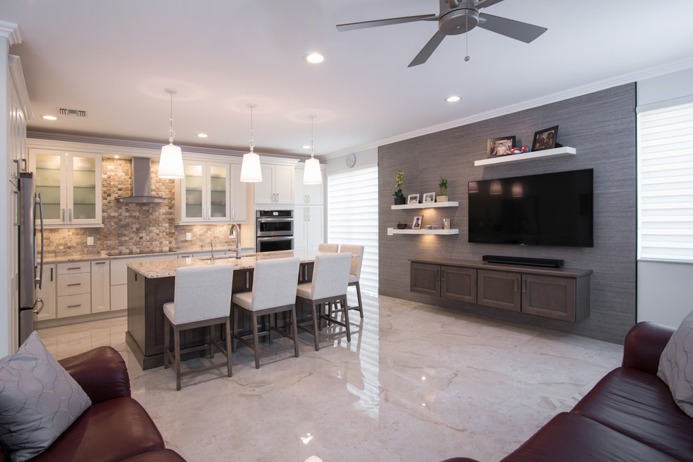 Large transitional l-shaped open concept kitchen photo in Miami with an undermount sink, shaker cabinets, white cabinets, granite countertops, beige backsplash, stone tile backsplash, stainless steel appliances and an island