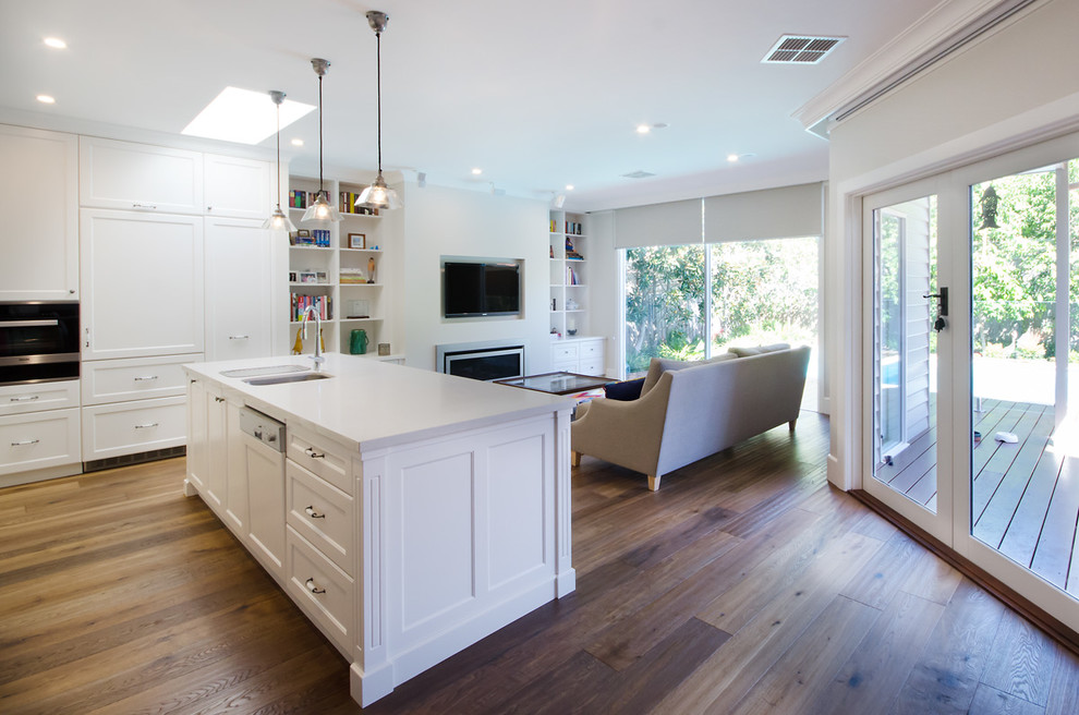 This is an example of a large traditional l-shaped kitchen pantry in Melbourne with an undermount sink, shaker cabinets, white cabinets, quartz benchtops, beige splashback, metal splashback, stainless steel appliances, medium hardwood floors and with island.