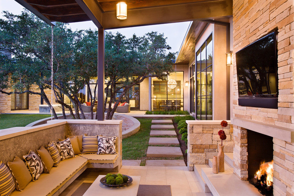 Photo of a large contemporary backyard patio in Austin with a fire feature, a roof extension and concrete pavers.