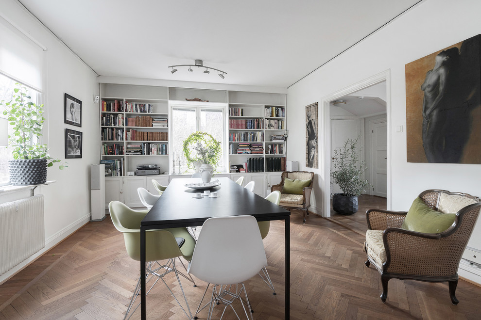 Photo of a mid-sized scandinavian separate dining room in Stockholm with white walls, medium hardwood floors, no fireplace and brown floor.