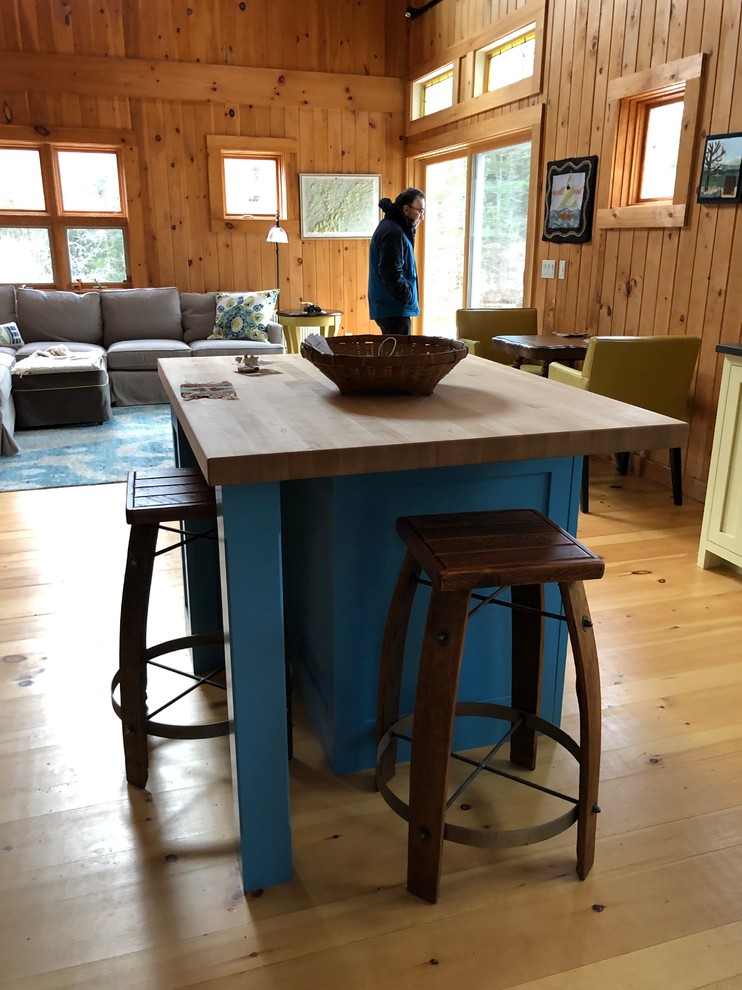 Arts and crafts kitchen in Portland Maine with a drop-in sink, shaker cabinets, yellow cabinets, wood benchtops, coloured appliances, light hardwood floors, with island, beige floor and brown benchtop.