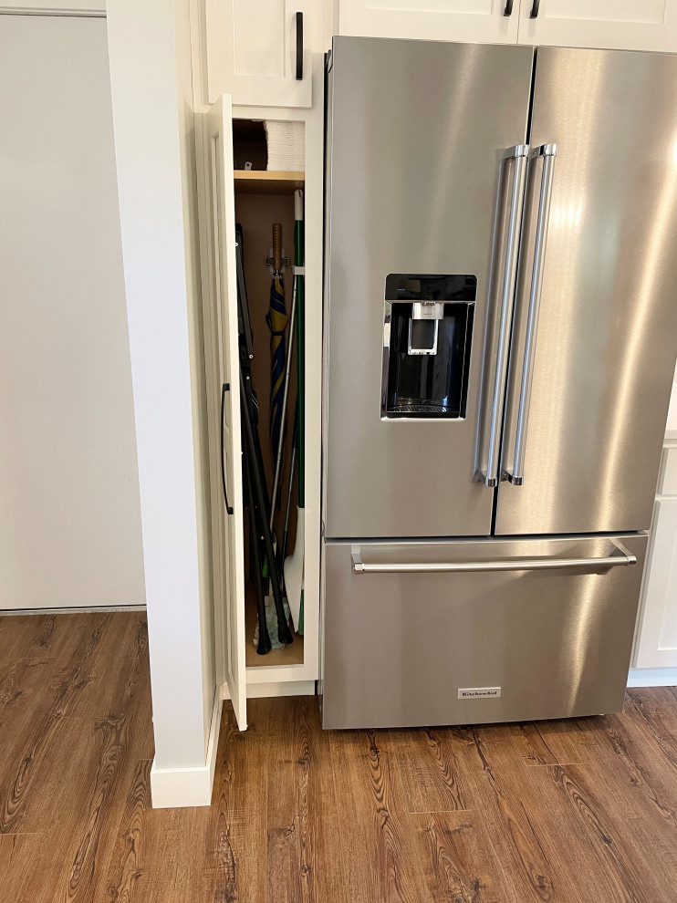 Large transitional u-shaped medium tone wood floor and brown floor open concept kitchen photo with an undermount sink, flat-panel cabinets, white cabinets, quartz countertops, multicolored backsplash, stone tile backsplash, stainless steel appliances, an island and white countertops