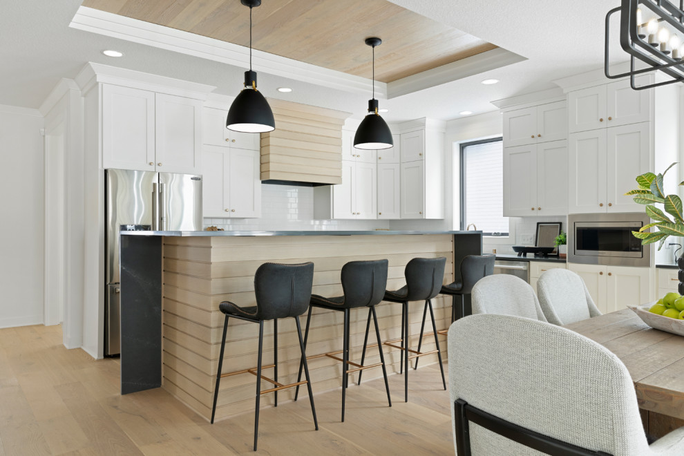 Design ideas for a scandinavian l-shaped eat-in kitchen in Minneapolis with shaker cabinets, quartzite benchtops, white splashback, stainless steel appliances, light hardwood floors, with island and wood.