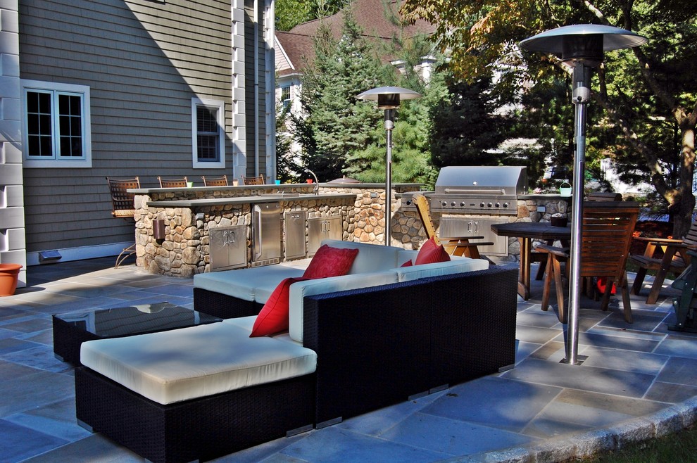 Photo of a large traditional backyard patio in New York with an outdoor kitchen and natural stone pavers.