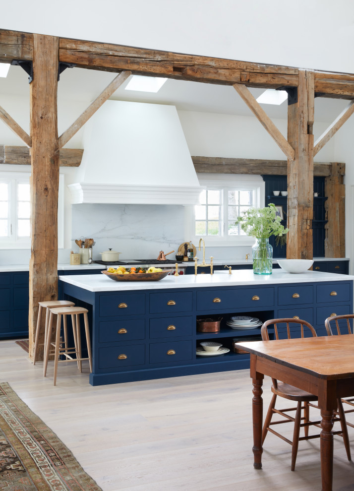 Expansive country u-shaped eat-in kitchen in Toronto with a farmhouse sink, flat-panel cabinets, blue cabinets, marble benchtops, white splashback, marble splashback, stainless steel appliances, light hardwood floors, with island, beige floor and white benchtop.