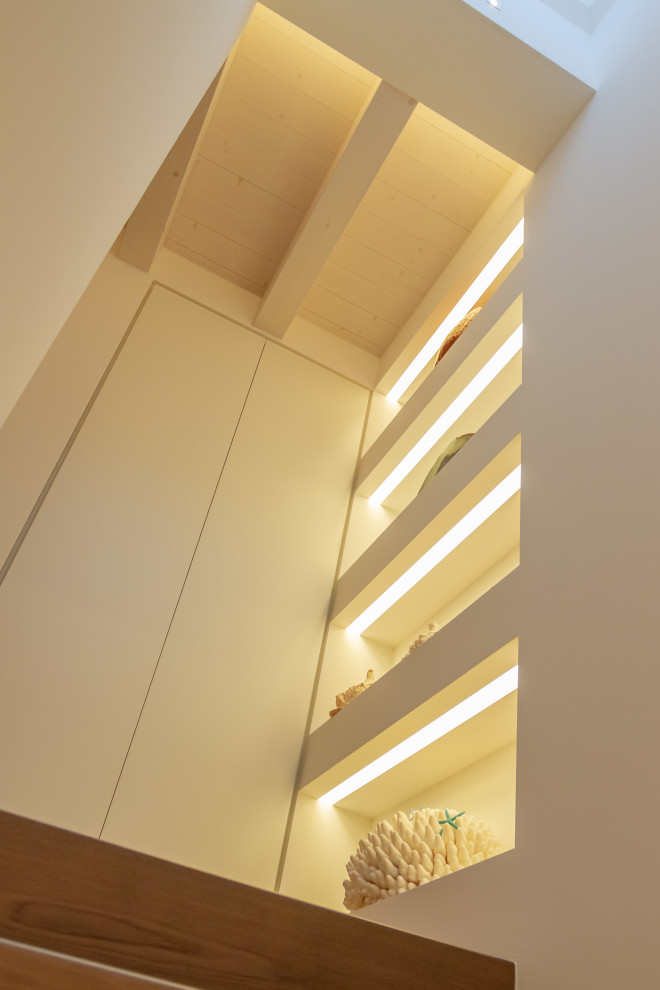 На фото: коридор в современном стиле с белыми стенами, деревянным полом, коричневым полом и балками на потолке с