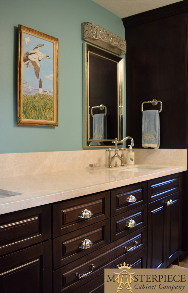Mid-sized beach style master bathroom in Houston with raised-panel cabinets, dark wood cabinets, a one-piece toilet, beige tile, stone slab, blue walls, medium hardwood floors, a drop-in sink and solid surface benchtops.