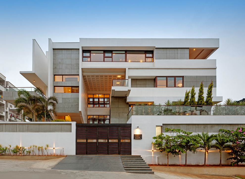 Inspiration for a contemporary three-storey multi-coloured house exterior in Bengaluru with a flat roof.
