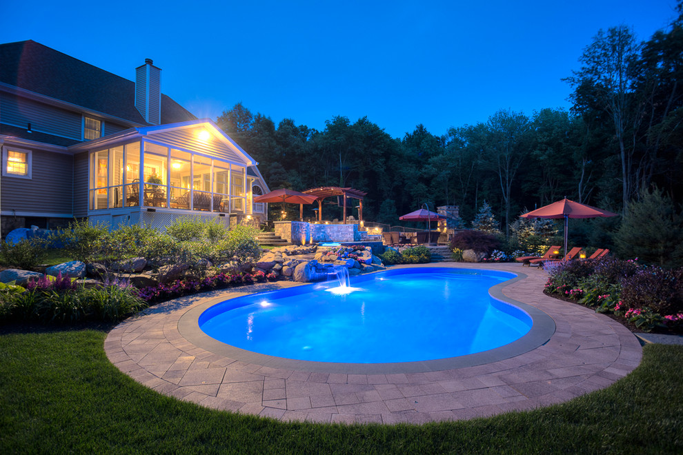 Photo of a large contemporary backyard kidney-shaped lap pool in New York with a hot tub and concrete pavers.