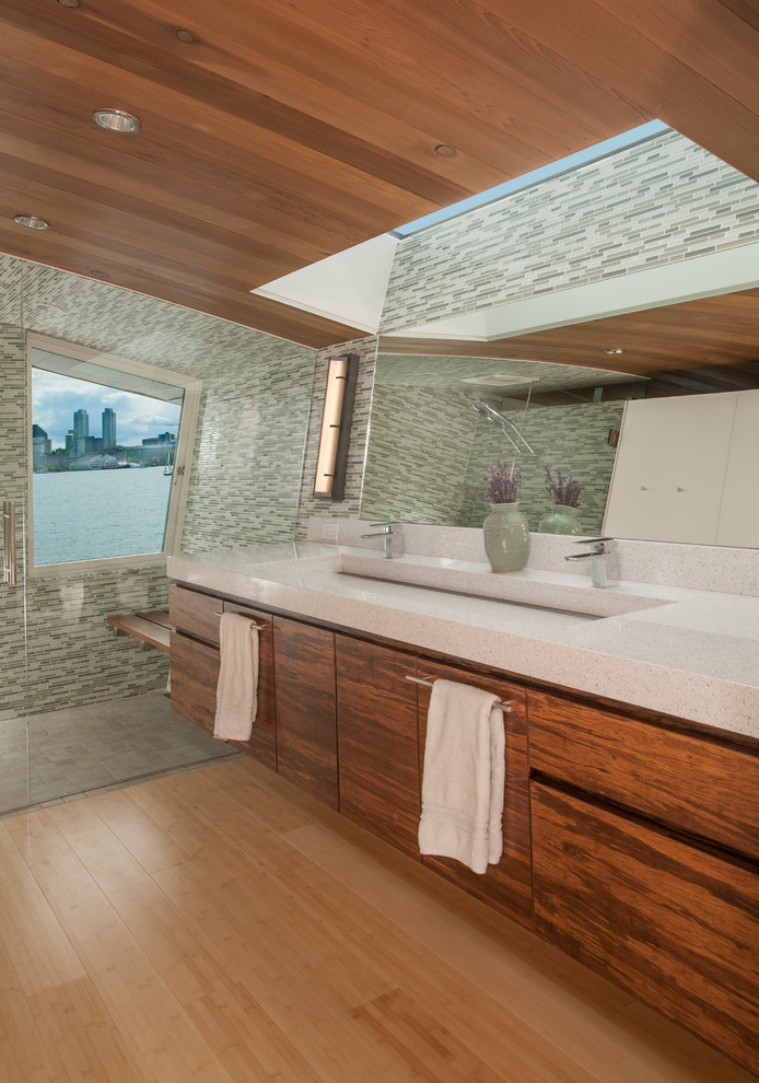 Design ideas for a beach style bathroom in Seattle with flat-panel cabinets, medium wood cabinets, a curbless shower, multi-coloured tile, mosaic tile, light hardwood floors and a trough sink.