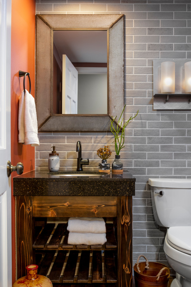 Bild på ett rustikt brun brunt toalett, med skåp i mörkt trä, en toalettstol med separat cisternkåpa, beige kakel, keramikplattor, orange väggar, mörkt trägolv, ett undermonterad handfat, bänkskiva i kvarts och brunt golv