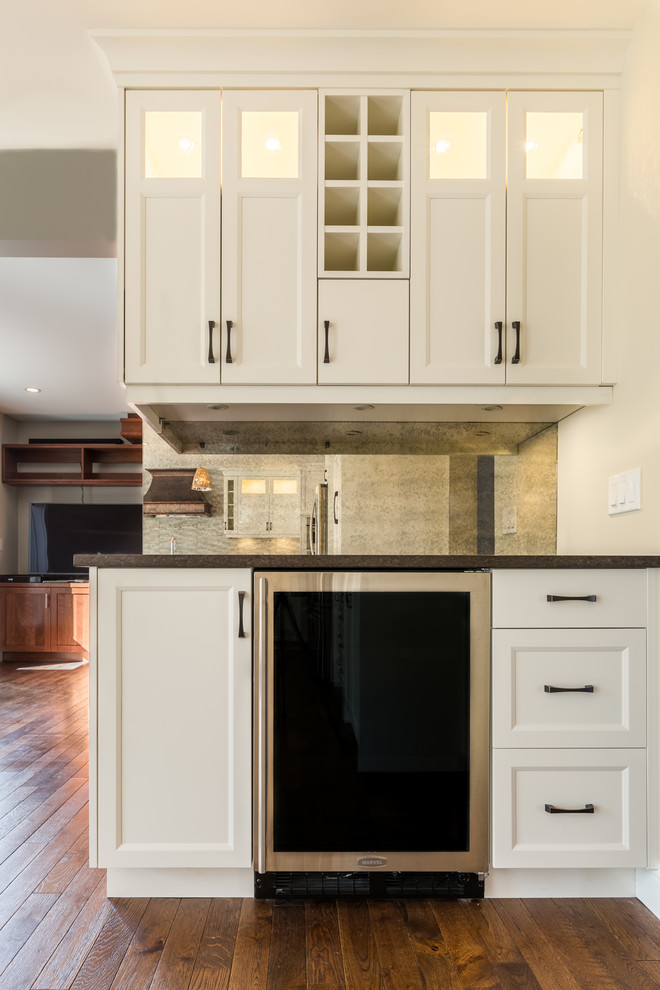 Inspiration for a mid-sized transitional u-shaped medium tone wood floor open concept kitchen remodel in Calgary with an undermount sink, recessed-panel cabinets, white cabinets, quartz countertops, gray backsplash, ceramic backsplash, stainless steel appliances and an island