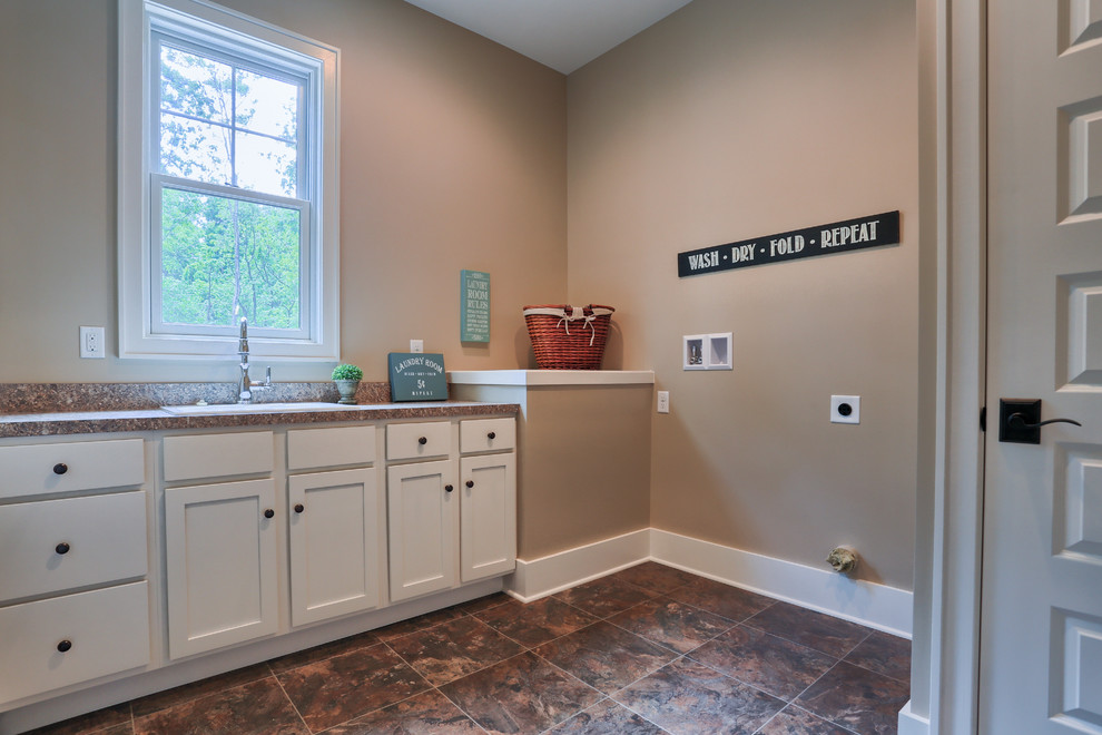 Photo of a large country dedicated laundry room in Other with white cabinets and beige walls.