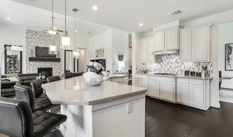 Mid-sized transitional l-shaped light wood floor, brown floor and coffered ceiling open concept kitchen photo in Houston with an undermount sink, shaker cabinets, white cabinets, quartzite countertops, gray backsplash, mosaic tile backsplash, black appliances, an island and gray countertops