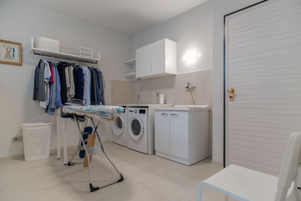 Design ideas for a mid-sized modern l-shaped utility room in Milan with a drop-in sink, flat-panel cabinets, turquoise cabinets, laminate benchtops, beige splashback, porcelain splashback, white walls, porcelain floors, a side-by-side washer and dryer, beige floor, white benchtop and recessed.