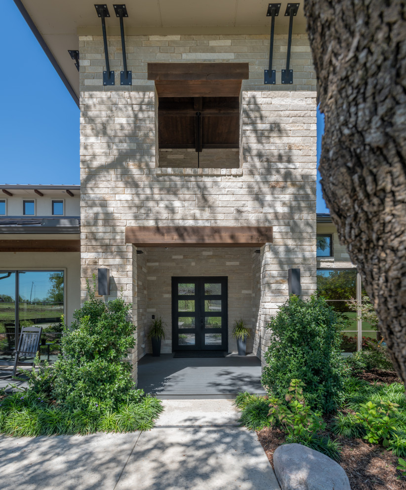 This is an example of an expansive transitional two-storey grey house exterior in Dallas with stone veneer.