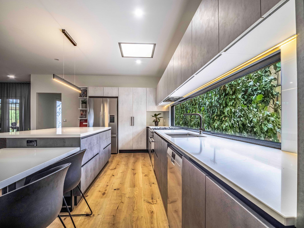 Inspiration for a contemporary u-shaped kitchen in Melbourne with a double-bowl sink, flat-panel cabinets, grey cabinets, stainless steel appliances, medium hardwood floors and brown floor.