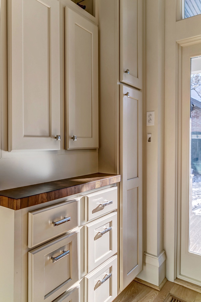 Inspiration for a transitional kitchen remodel with flat-panel cabinets, white cabinets, white backsplash, ceramic backsplash, stainless steel appliances, white walls and a peninsula