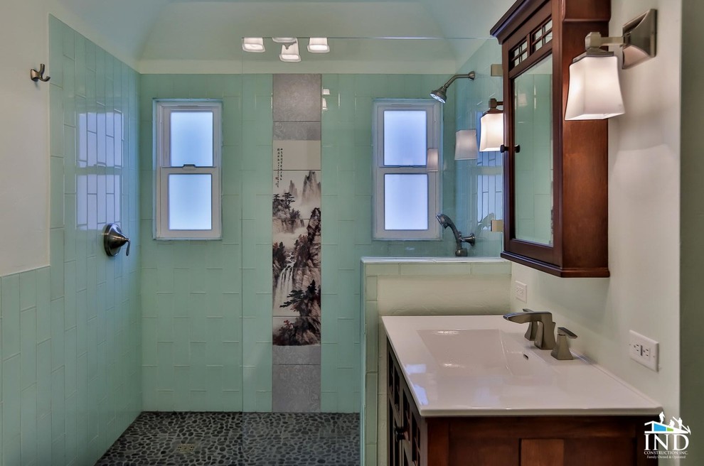 Photo of an asian 3/4 bathroom in Los Angeles with furniture-like cabinets, medium wood cabinets, a corner shower, a two-piece toilet, blue tile, glass tile, white walls, pebble tile floors and a trough sink.