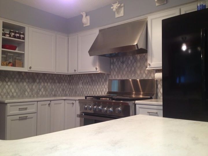 Inspiration for a small transitional u-shaped eat-in kitchen remodel in Chicago with a farmhouse sink, recessed-panel cabinets, white cabinets, marble countertops, gray backsplash, mosaic tile backsplash, black appliances and a peninsula