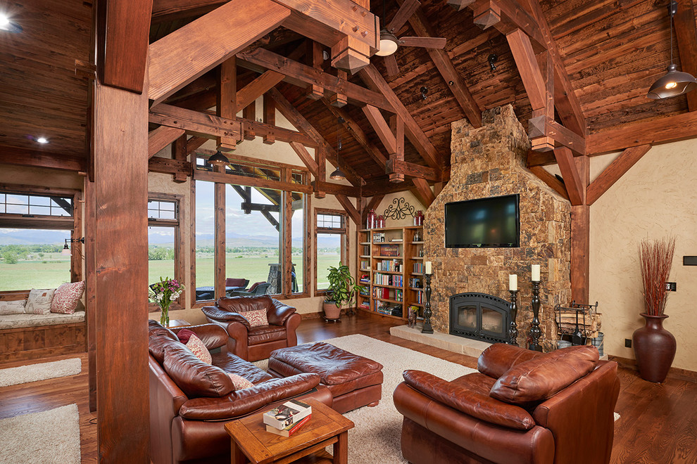 Design ideas for a country family room in Denver with a library, beige walls, medium hardwood floors, a standard fireplace and a wall-mounted tv.