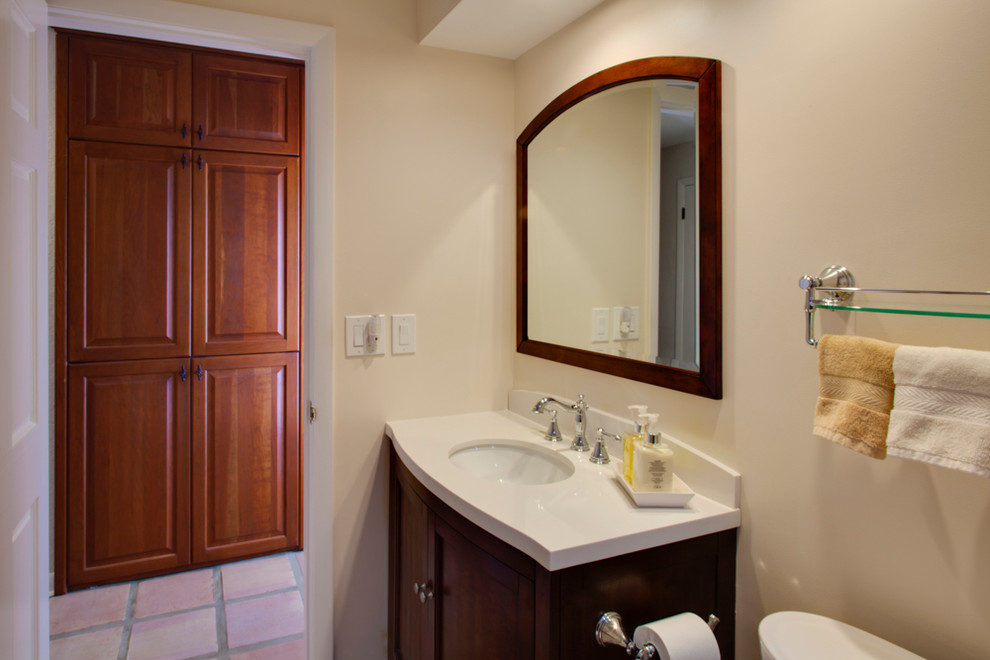 This is an example of a small traditional 3/4 bathroom in Tampa with shaker cabinets, dark wood cabinets, an alcove shower, a one-piece toilet, beige tile, travertine, beige walls, terra-cotta floors, an undermount sink, stainless steel benchtops, beige floor and a shower curtain.