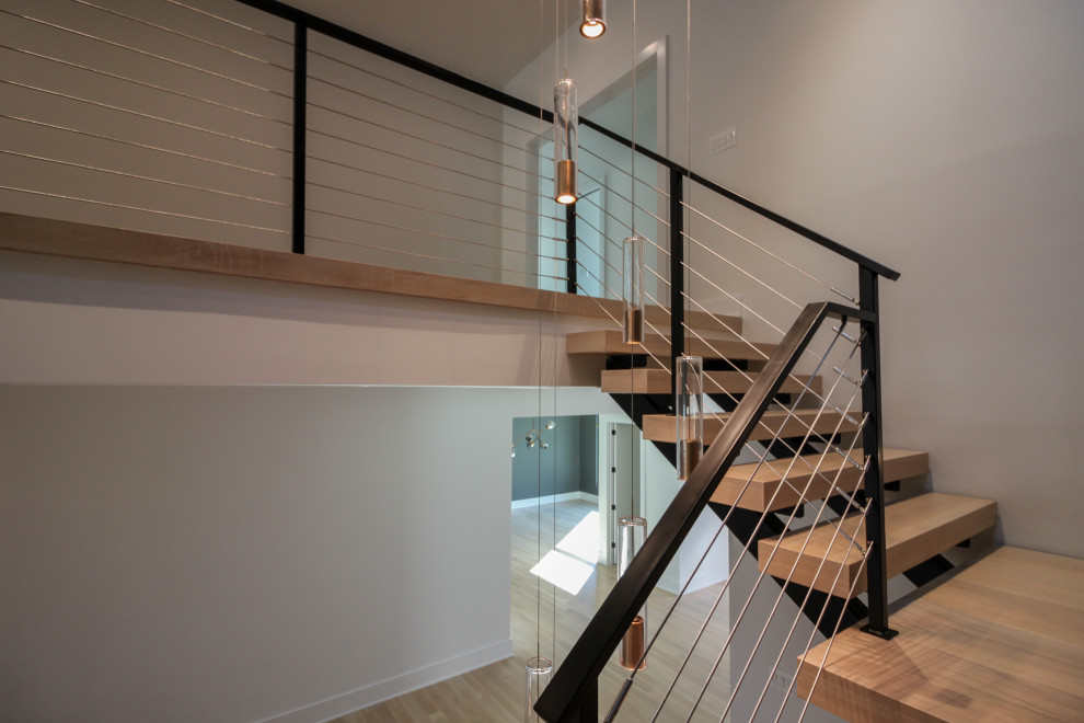 Diseño de escalera suspendida ecléctica grande con escalones de madera, barandilla de metal y ladrillo