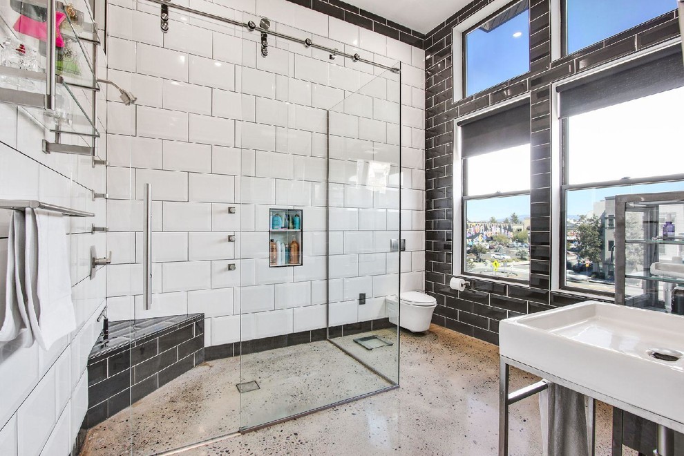 Mid-sized industrial master bathroom in Orange County with furniture-like cabinets, distressed cabinets, an open shower, a wall-mount toilet, black and white tile, porcelain tile, concrete floors, a console sink, solid surface benchtops, grey floor and a sliding shower screen.