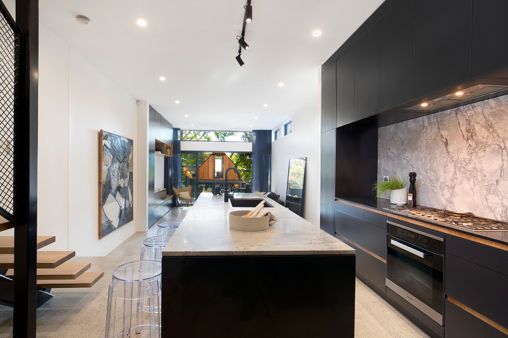 Inspiration for a contemporary galley open plan kitchen in Sydney with an undermount sink, flat-panel cabinets, black cabinets, marble benchtops, marble splashback, stainless steel appliances, concrete floors, with island, grey splashback, grey floor and grey benchtop.
